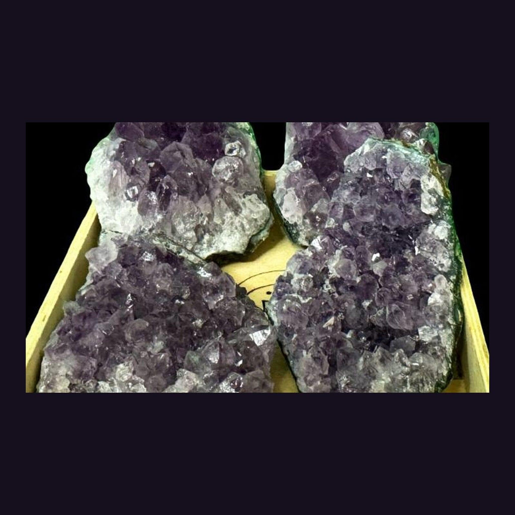 Tray of large amethyst geode clusters packed together, showing the range of sizes available in the shop.