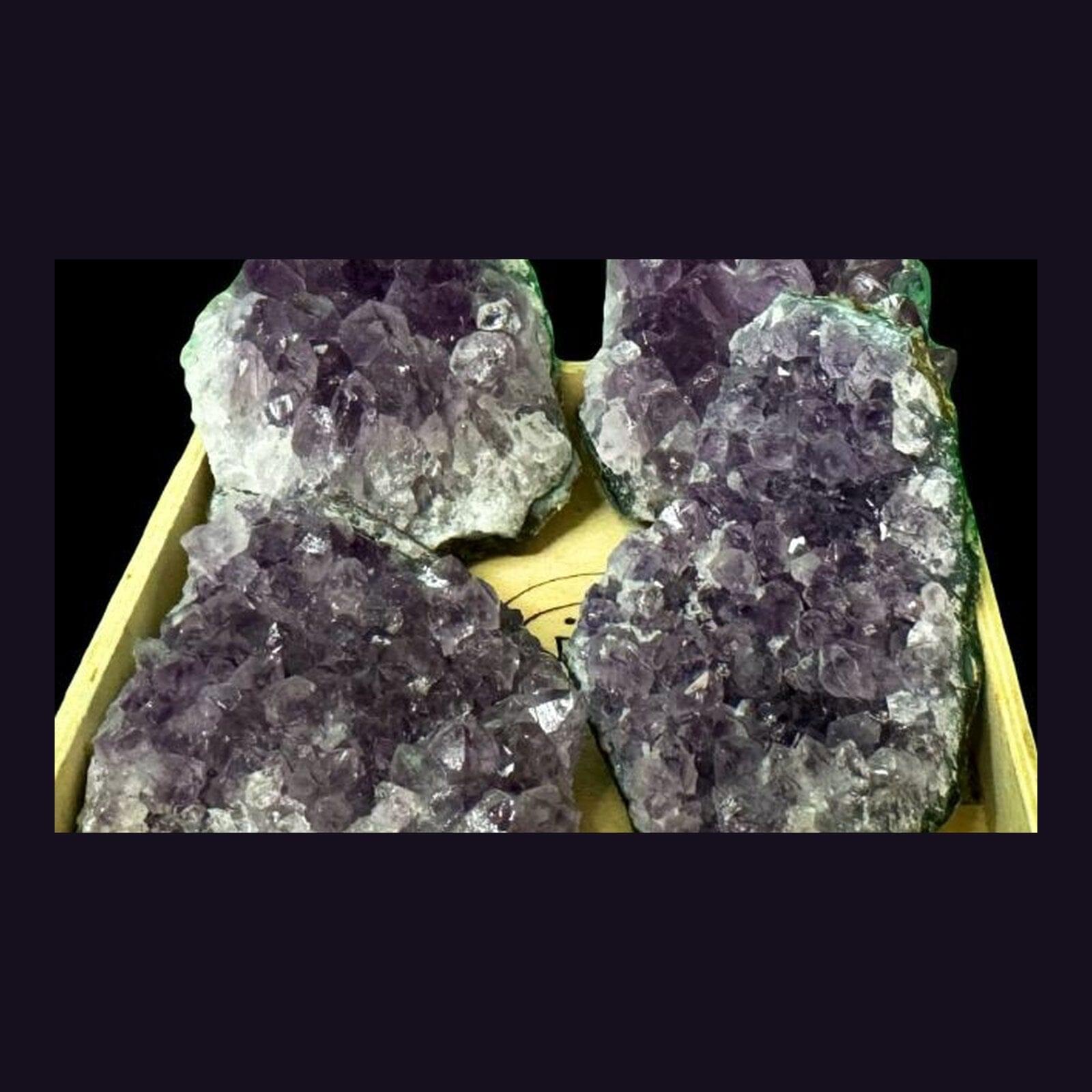 Tray of large amethyst geode clusters packed together, showing the range of sizes available in the shop.